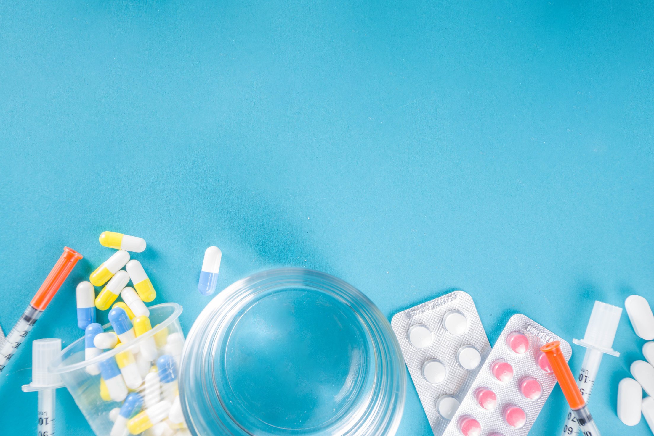 Prescription Drugs, Water Glass and Syringe on Blue Background